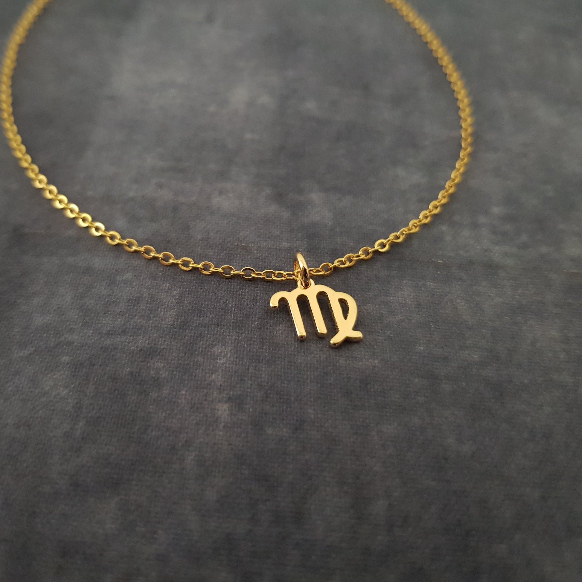 a gold necklace with the letter m on it