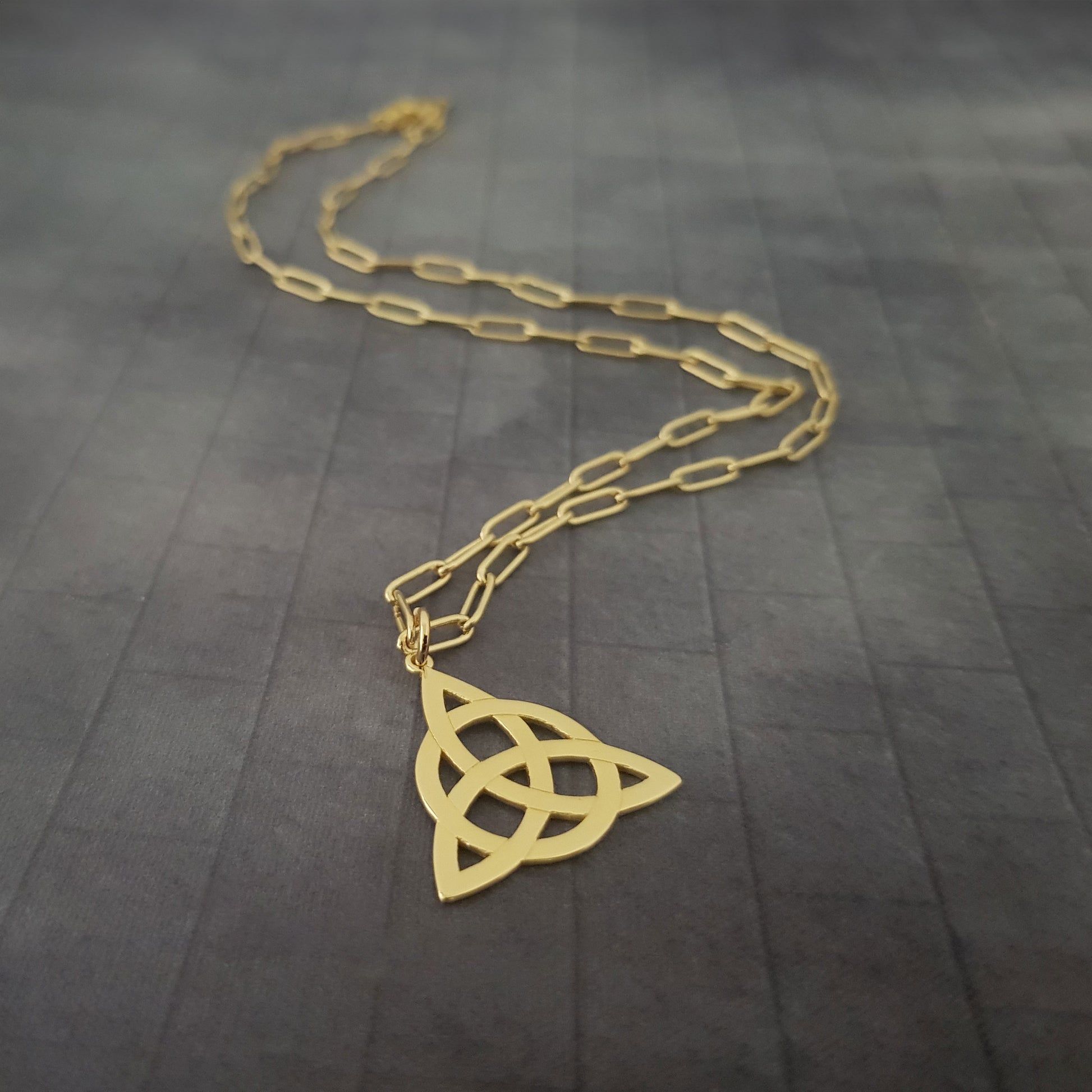 a gold necklace with a celtic knot on it