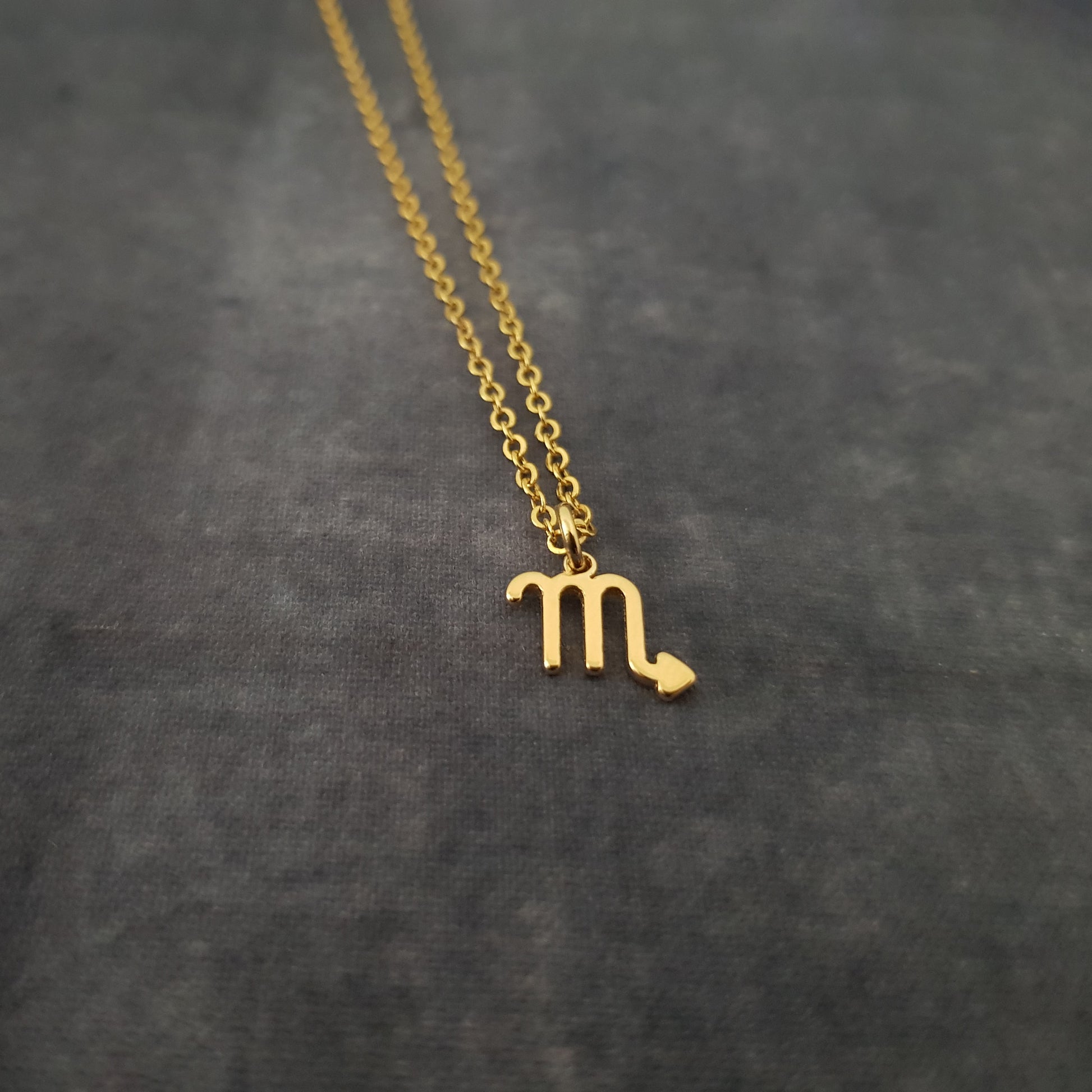 a gold necklace with the letter m on it