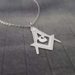 a silver necklace with a masonic symbol on it