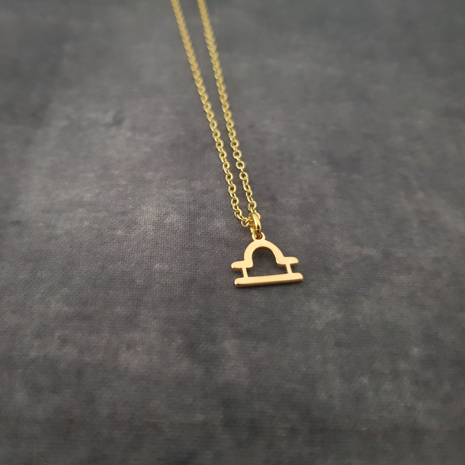 a gold necklace with a small house on it