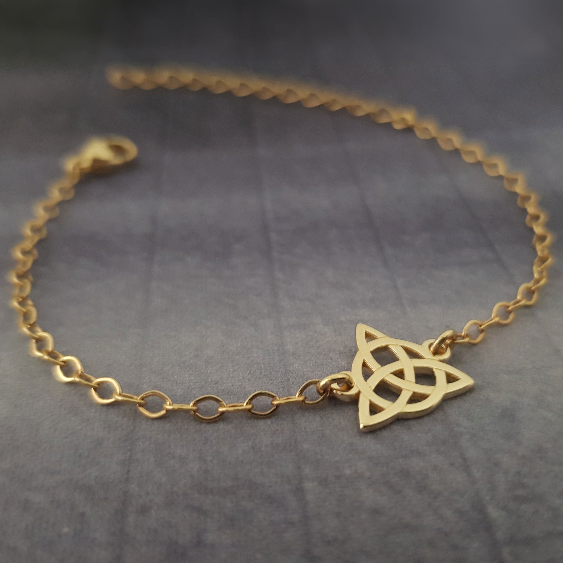 a gold bracelet with a celtic knot on it