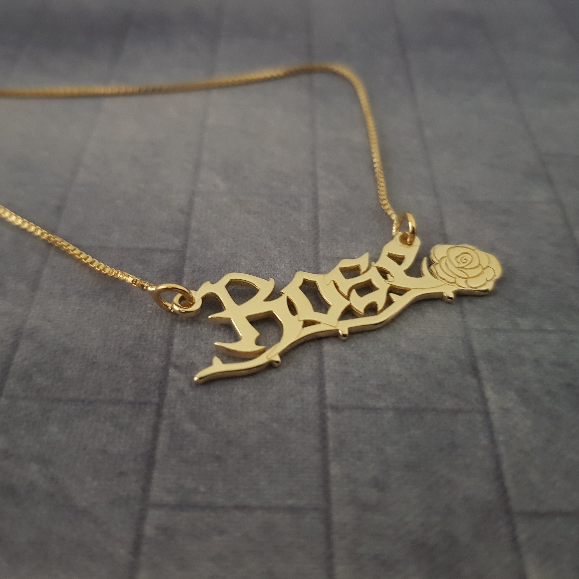 a gold necklace with a rose on it