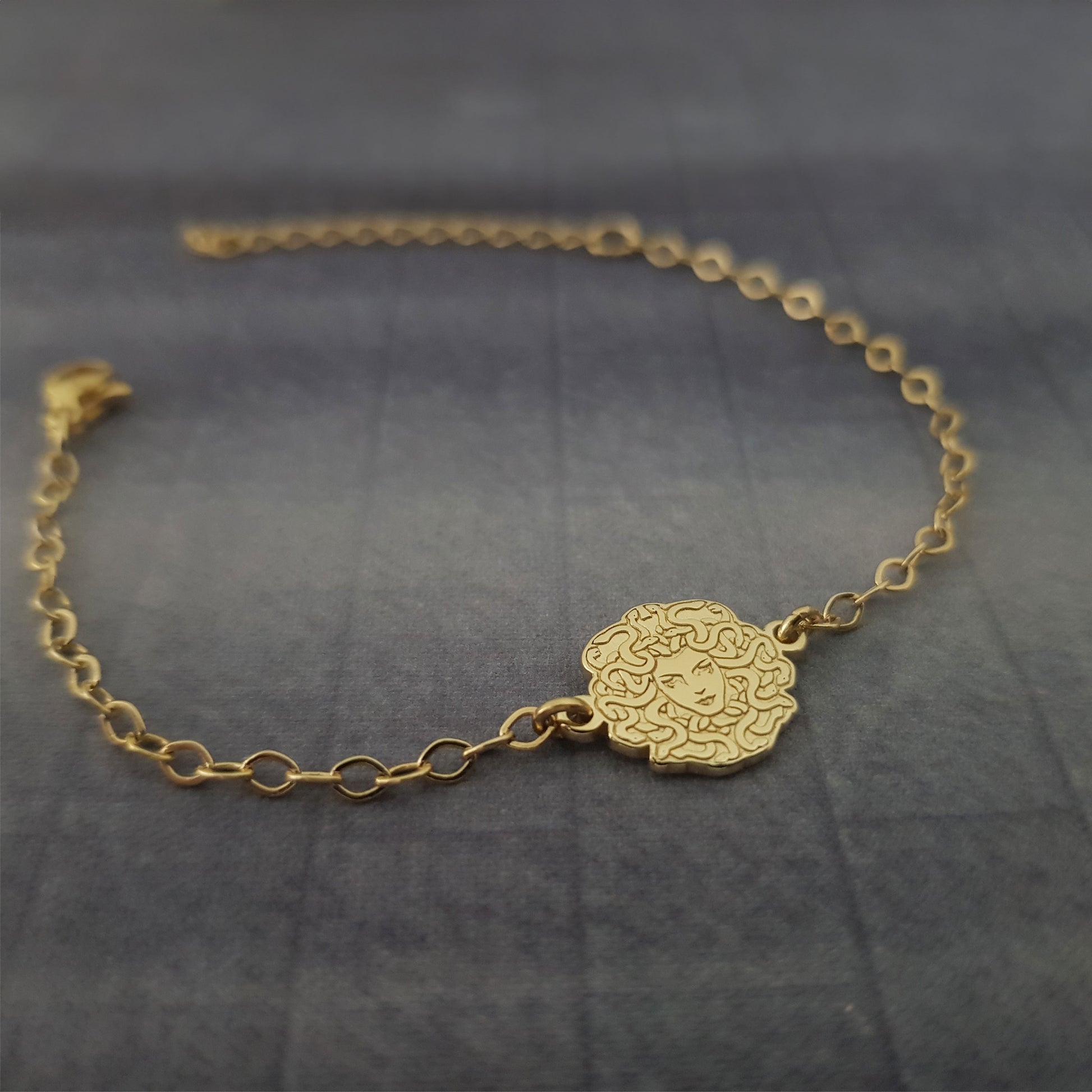 a gold chain bracelet with a flower design on it