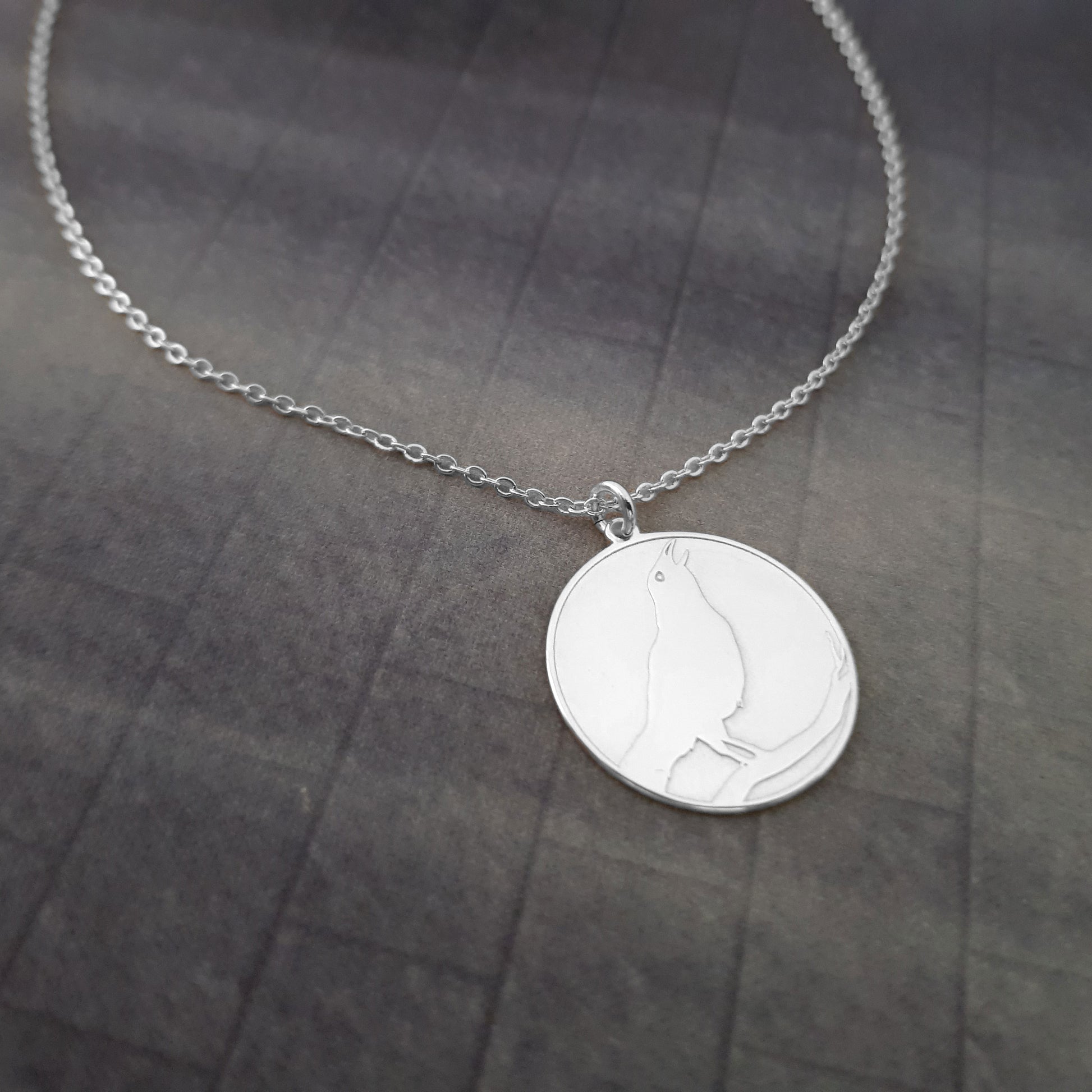 a silver necklace with a bird on it