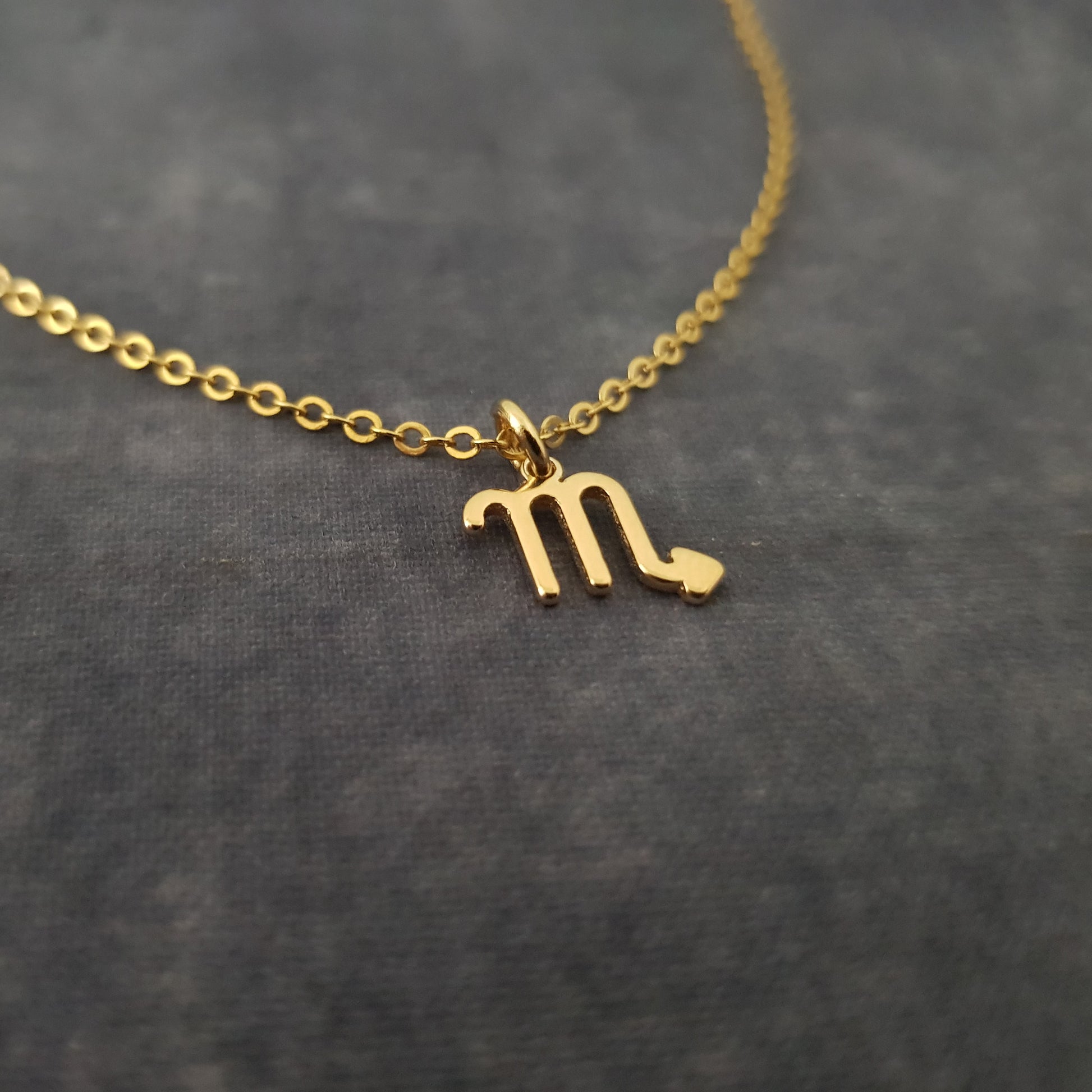 a gold necklace with the letter m on it