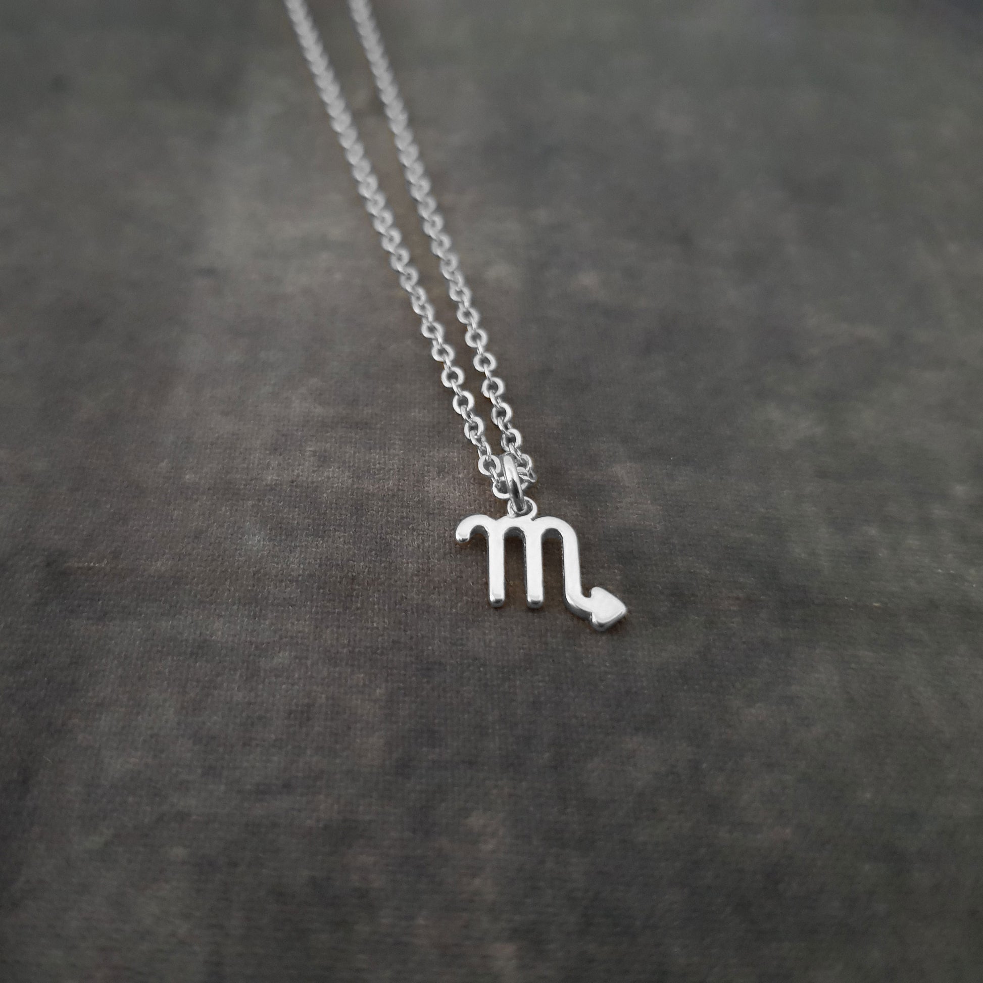 a silver necklace with the letter m on it