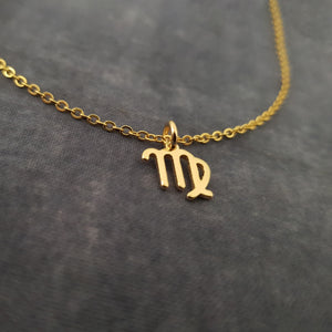 a gold necklace with the letter m on it