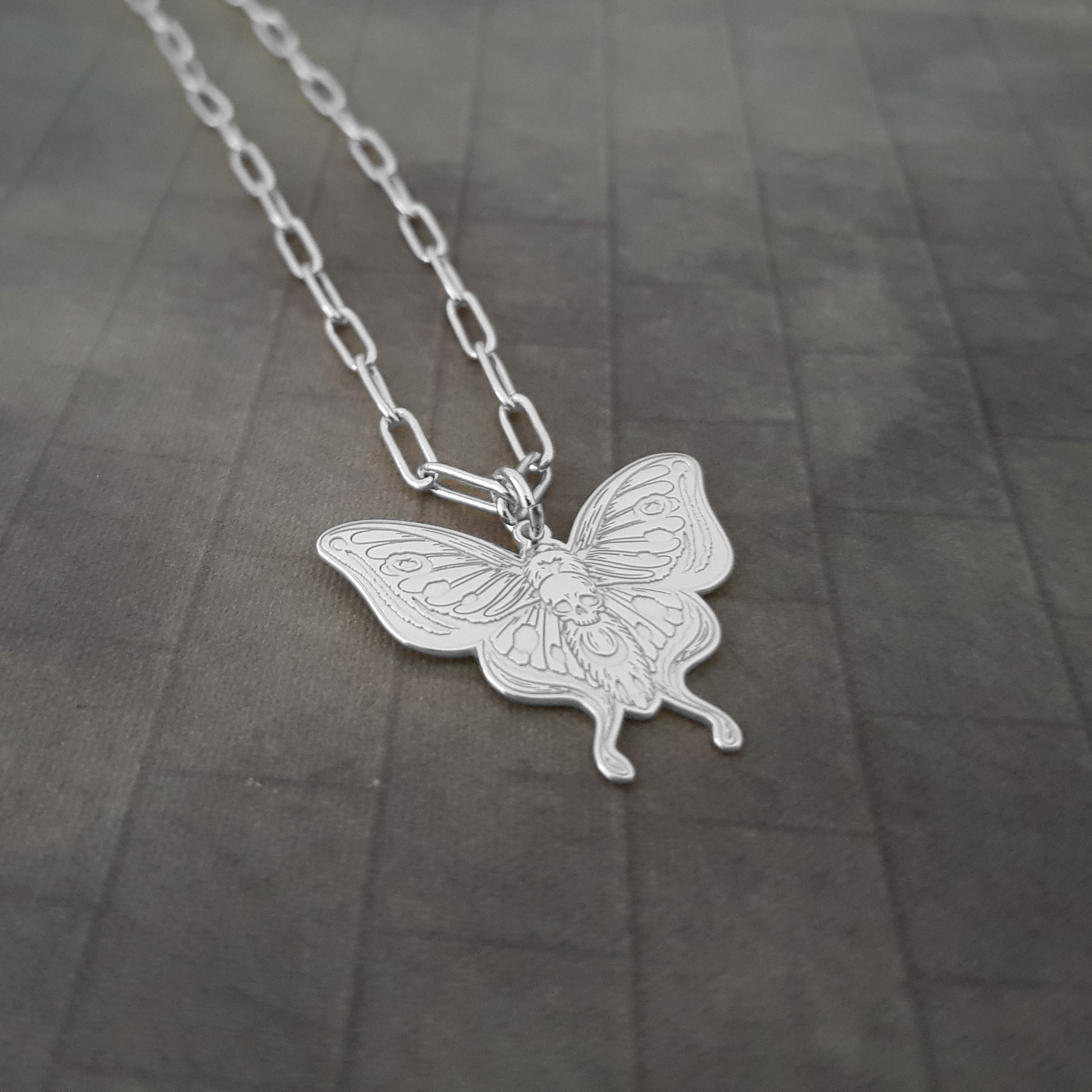 a silver necklace with a butterfly on it