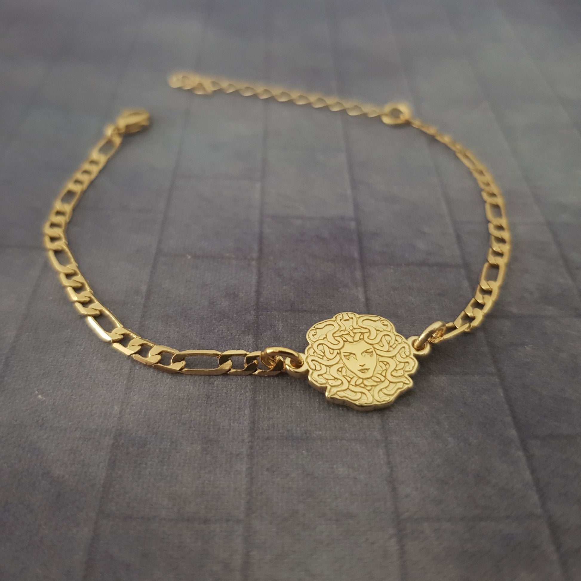 a gold chain bracelet with a skull charm