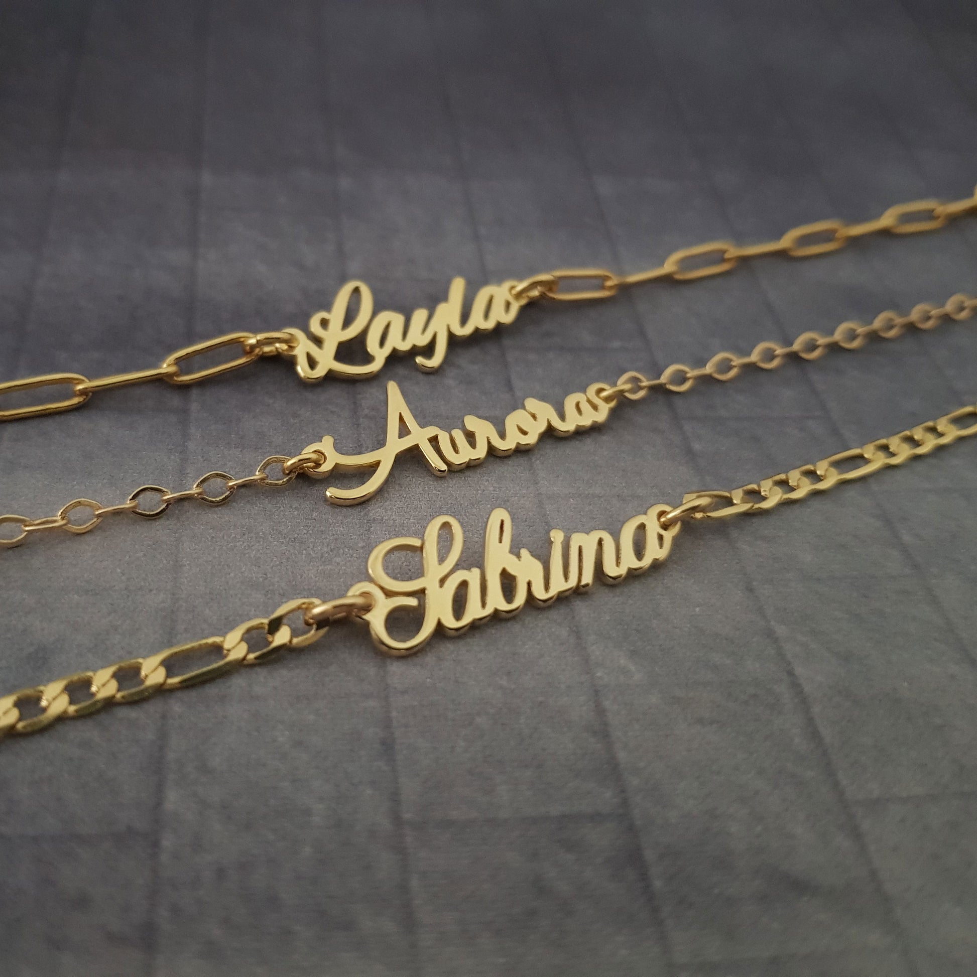 three personalized name necklaces on a table