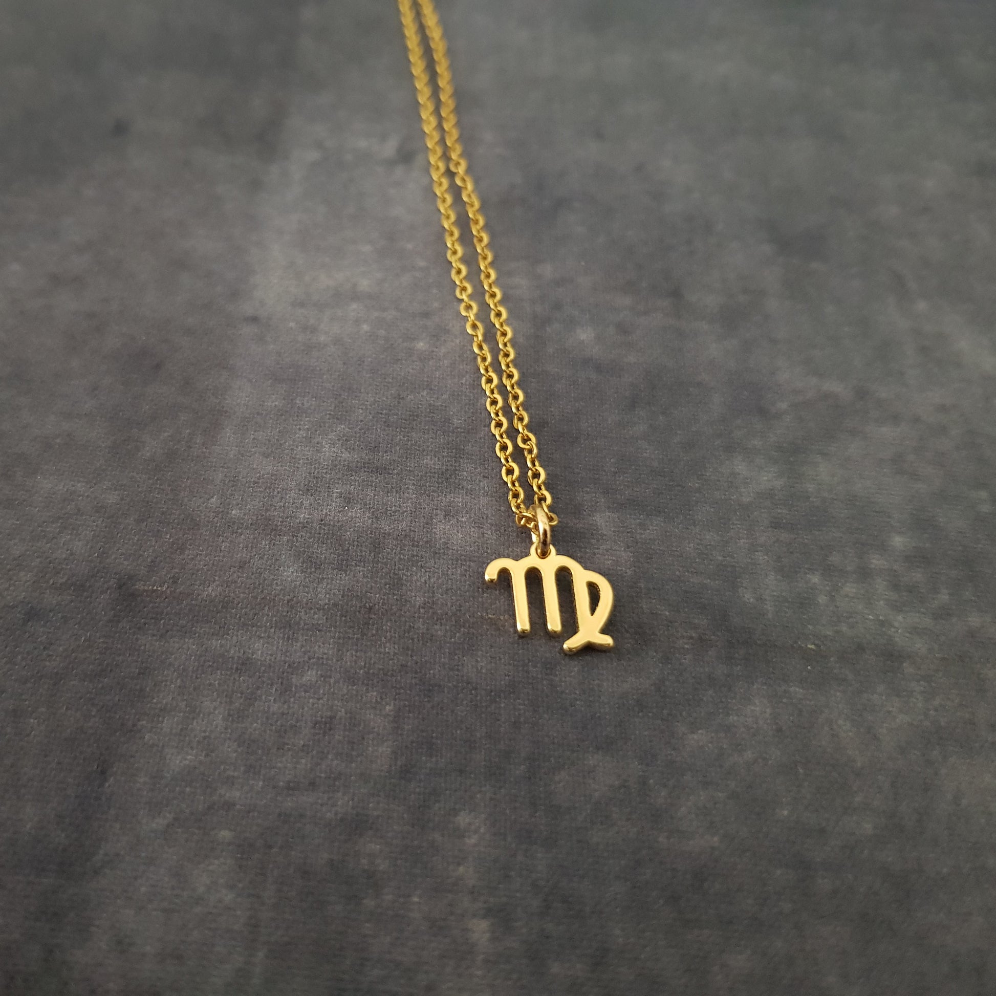 a gold necklace with the letter pi on it