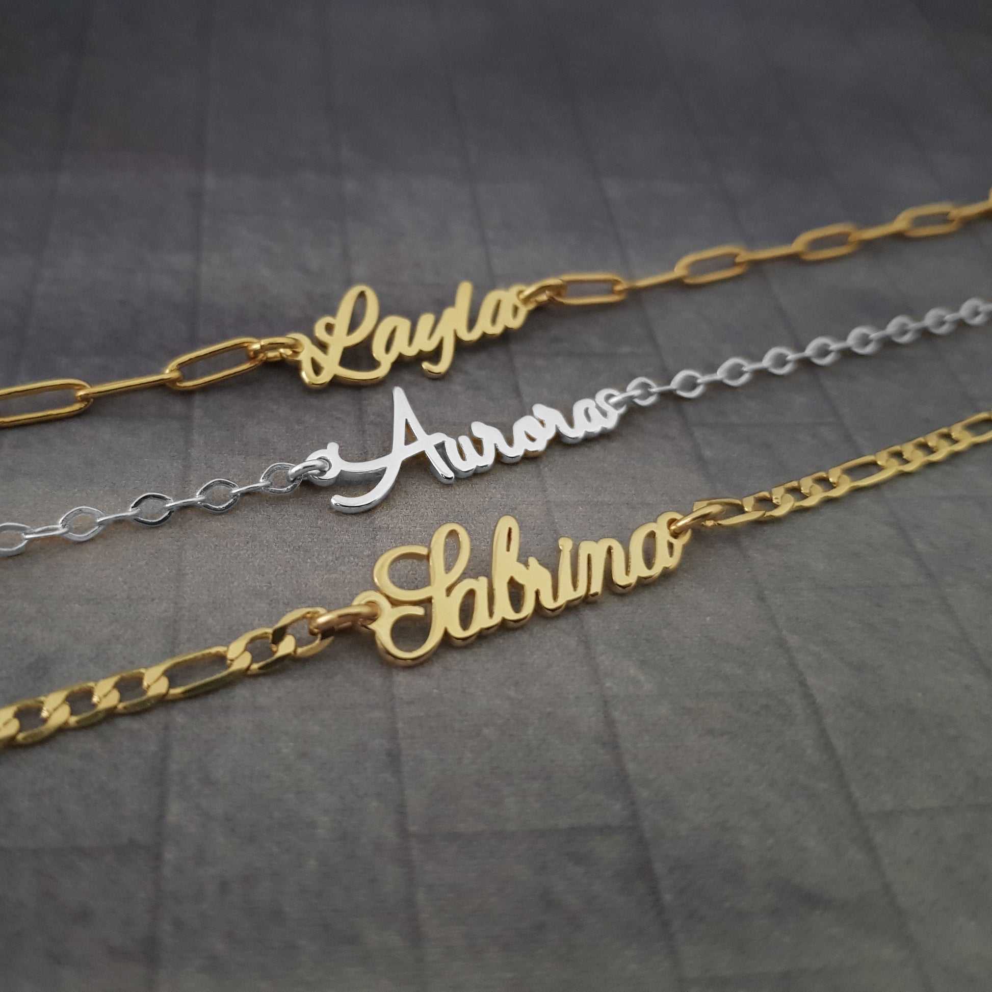 three personalized name necklaces on a table