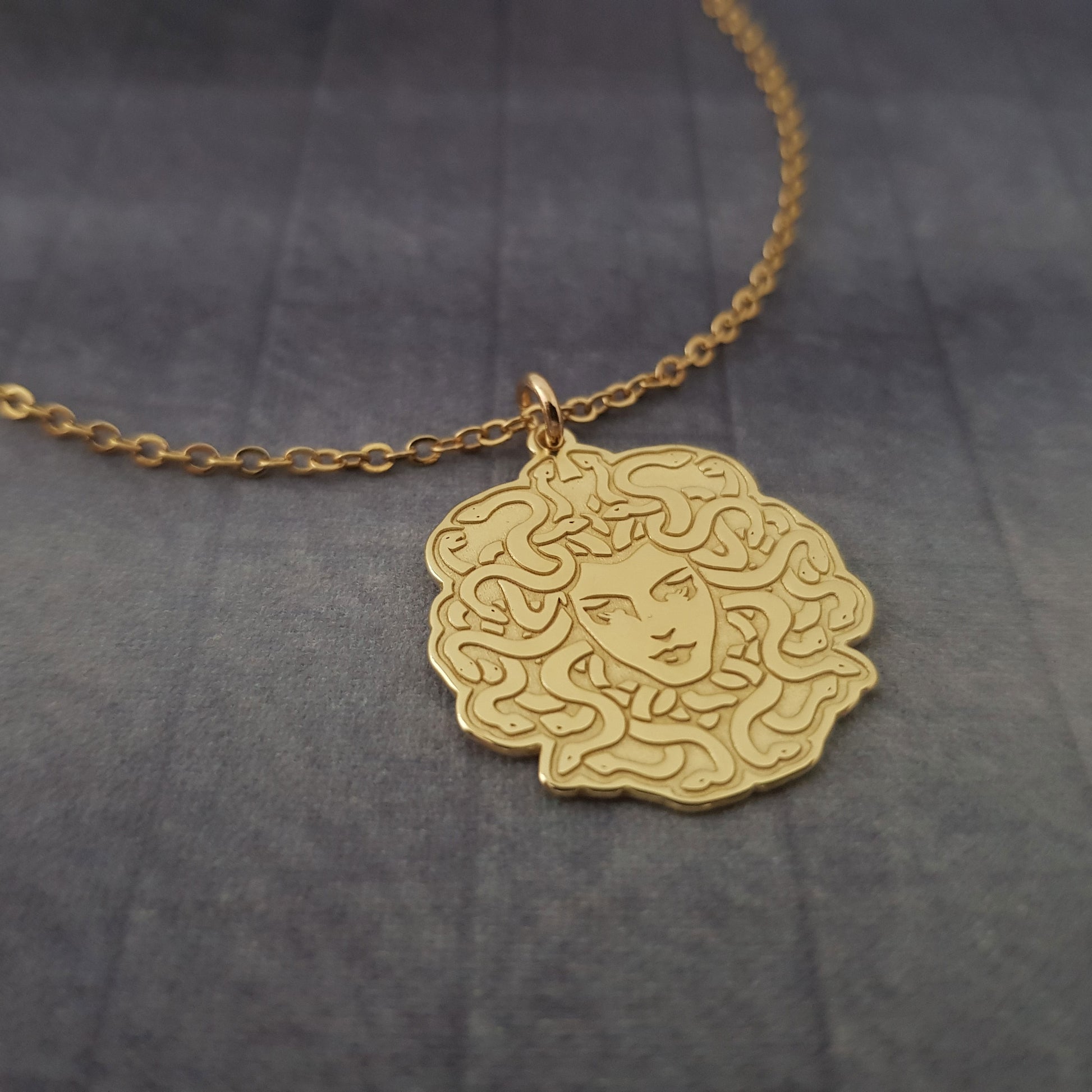 a gold necklace with a woman's face on it