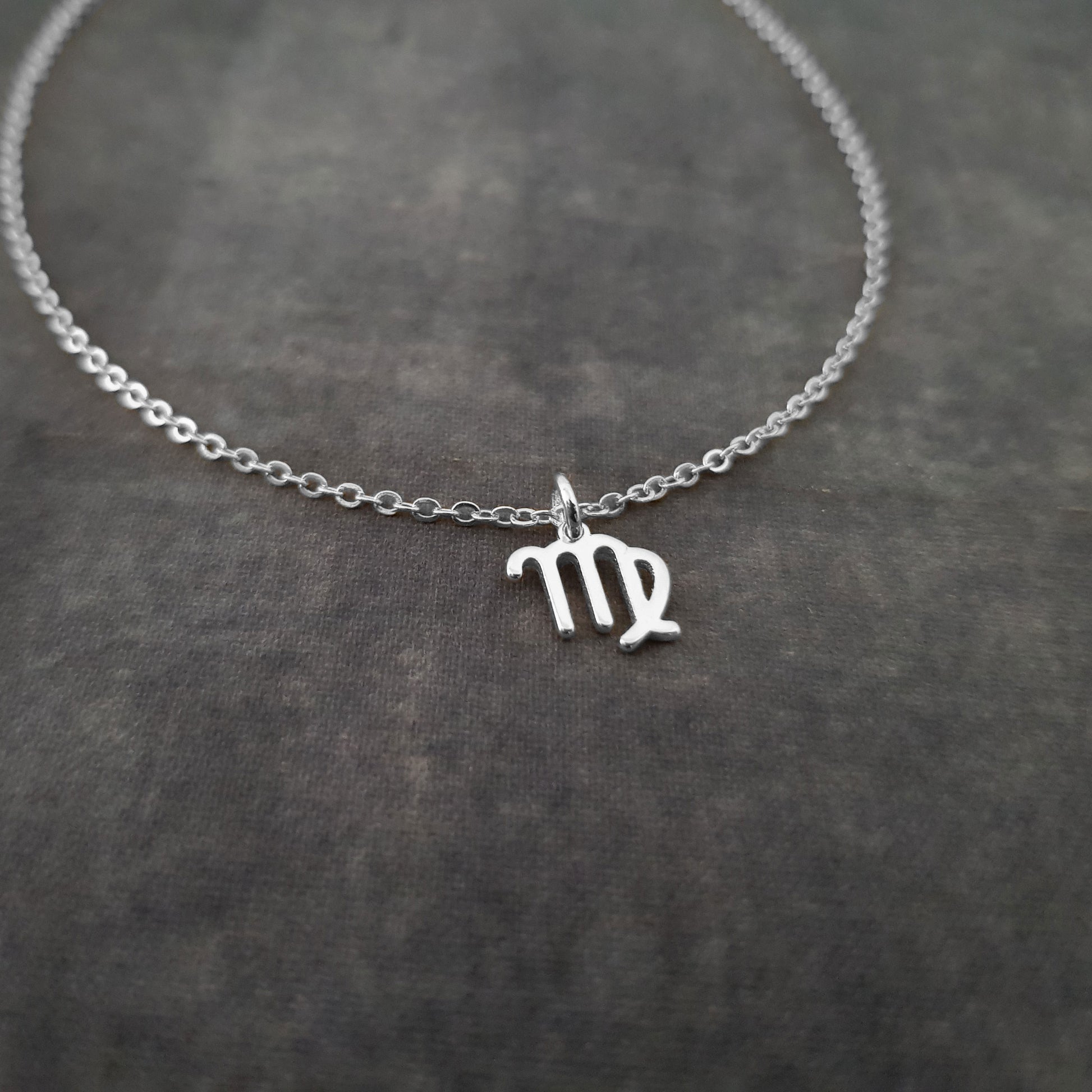 a silver necklace with the letter m on it