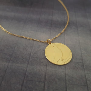 a gold necklace with a cat on it