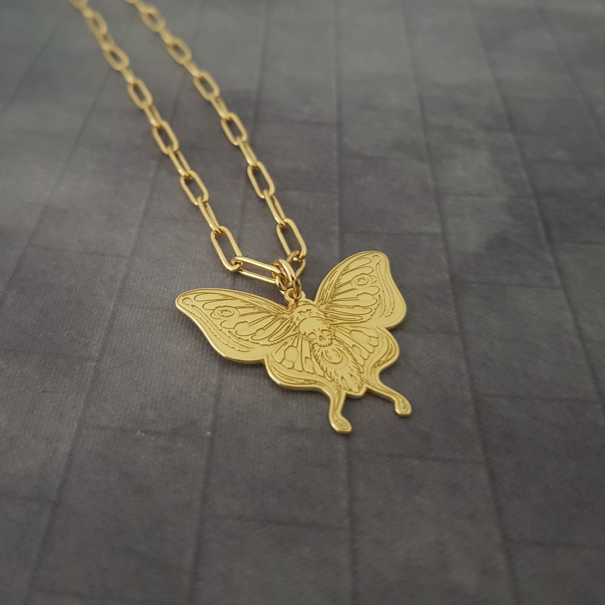 a gold necklace with a butterfly on it