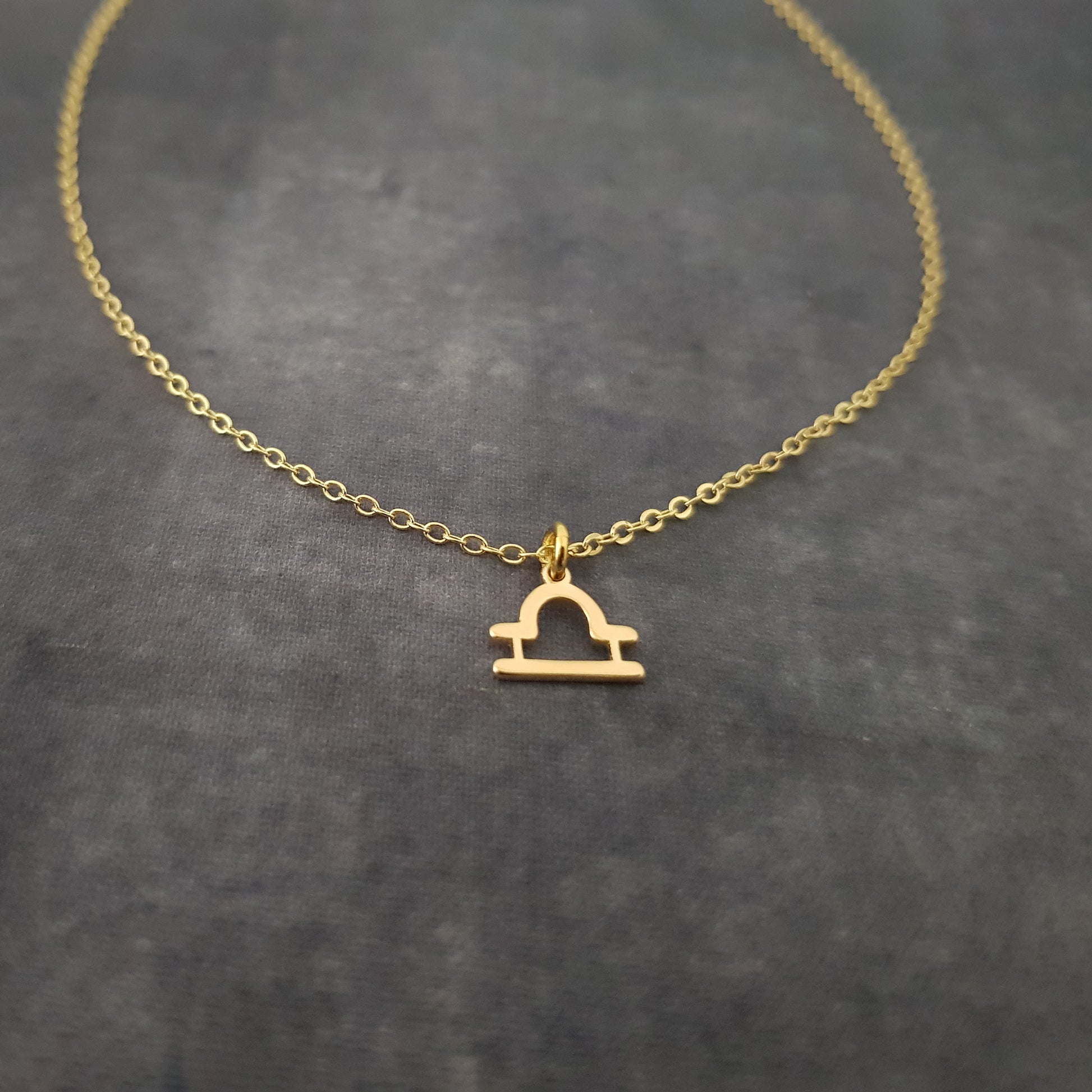 a gold necklace with a small arch on it