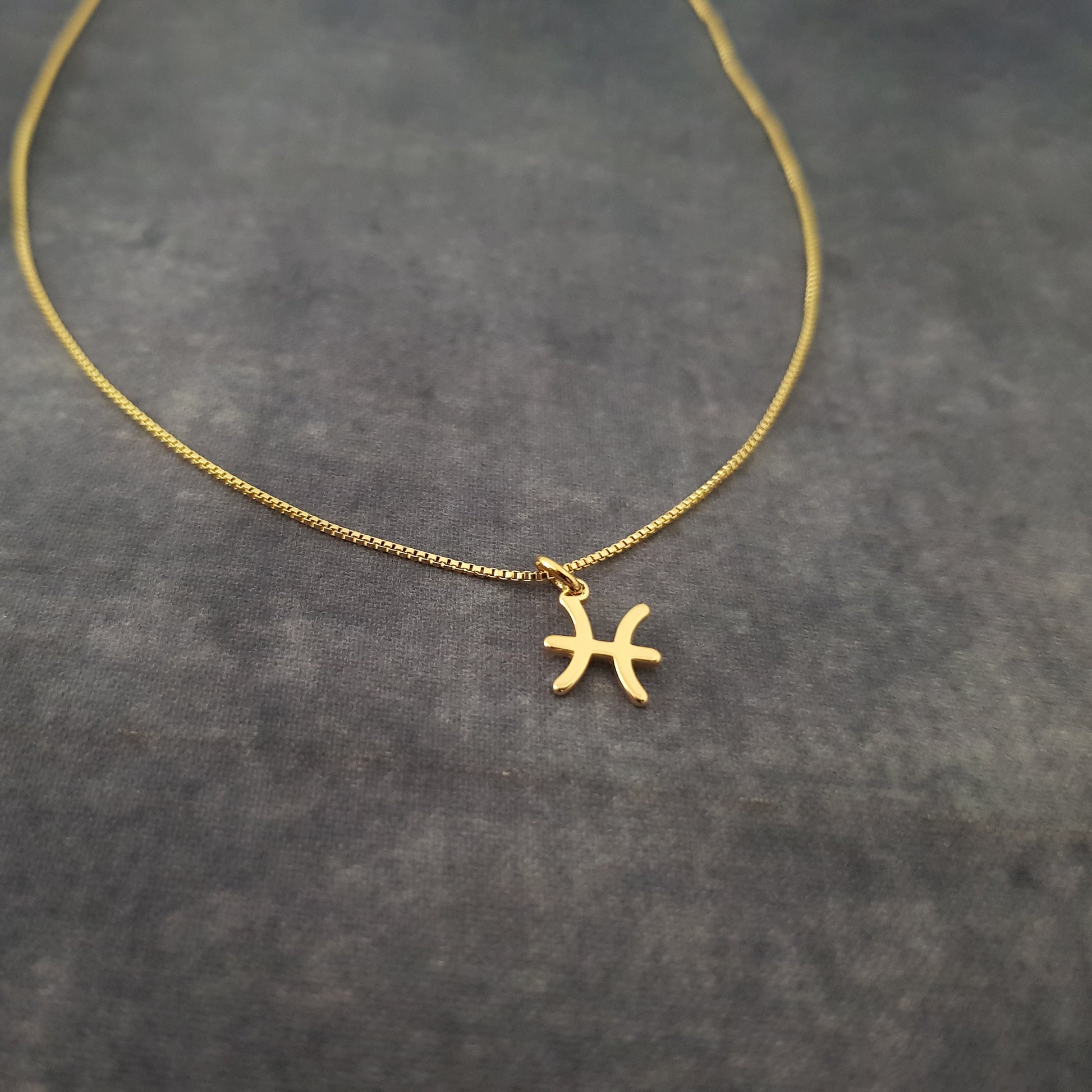 a gold necklace with a zodiac sign on it