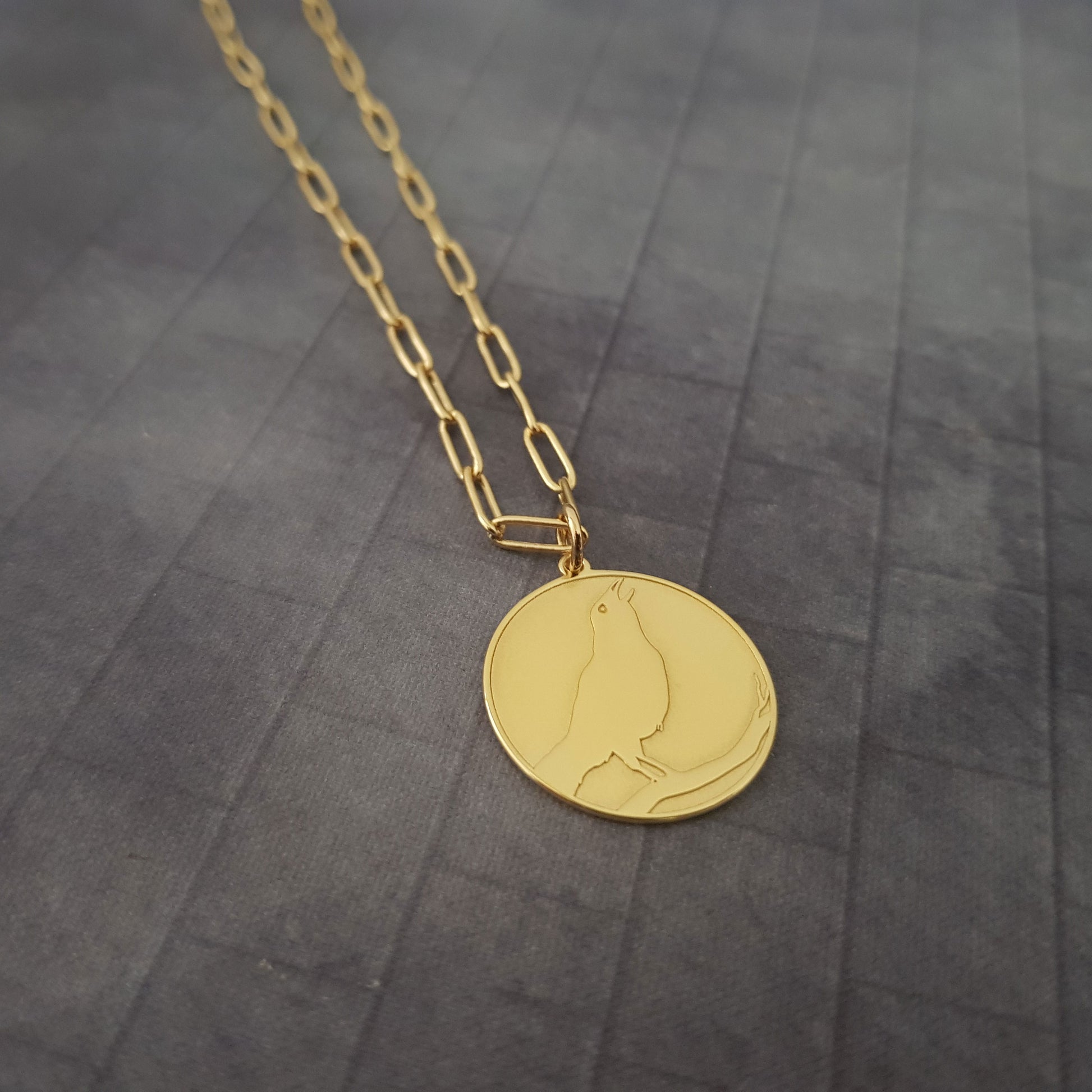 a gold necklace with a bird on it