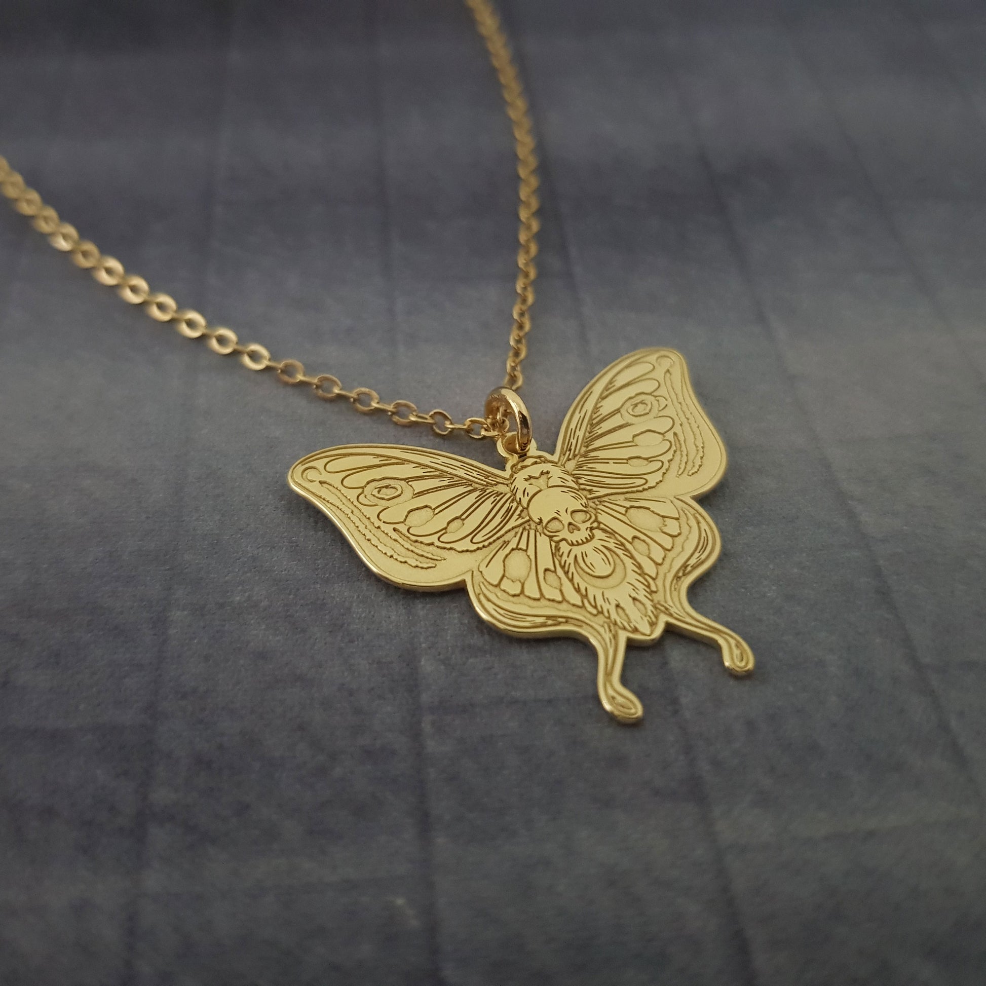 a gold necklace with a butterfly on it