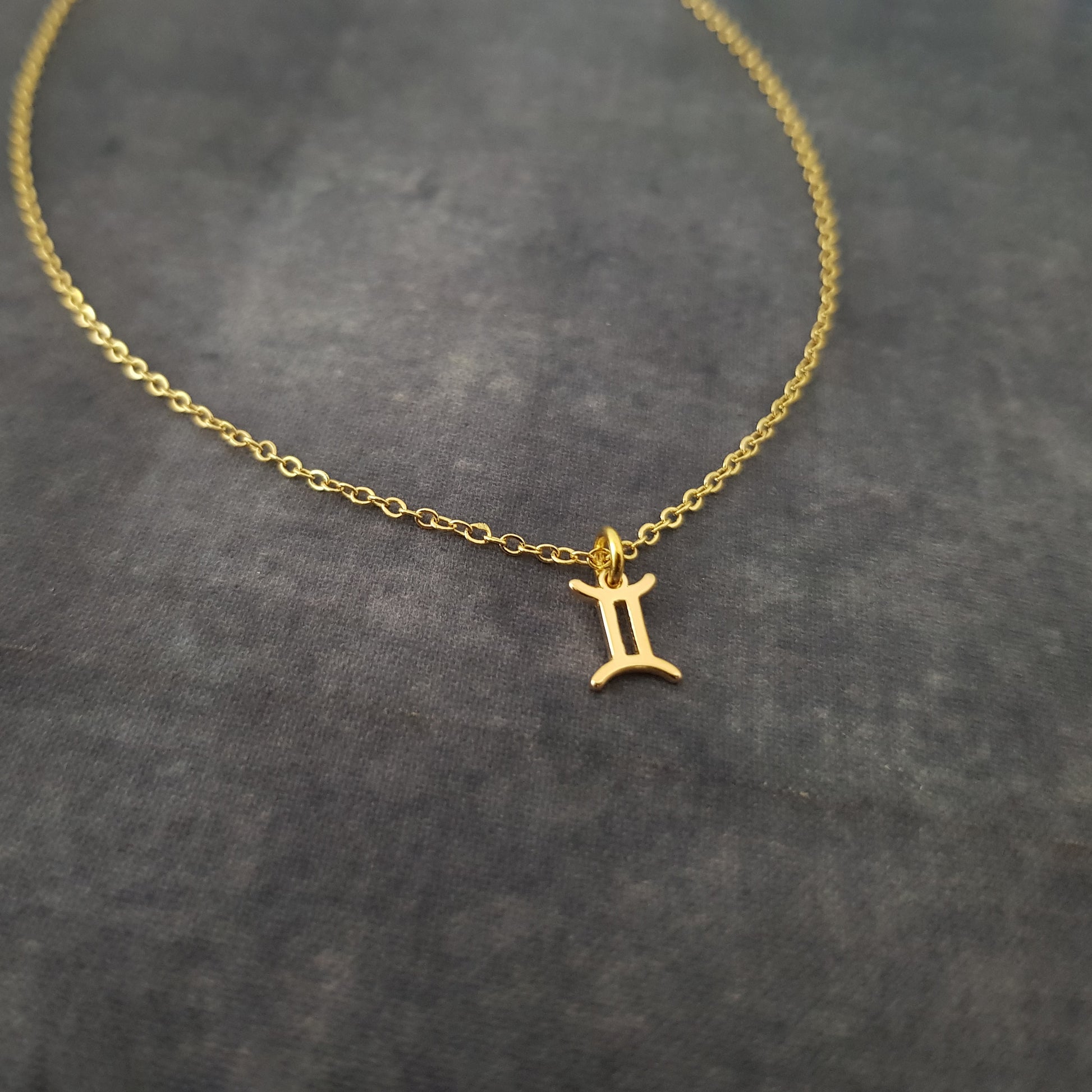 a gold necklace with the letter i on it