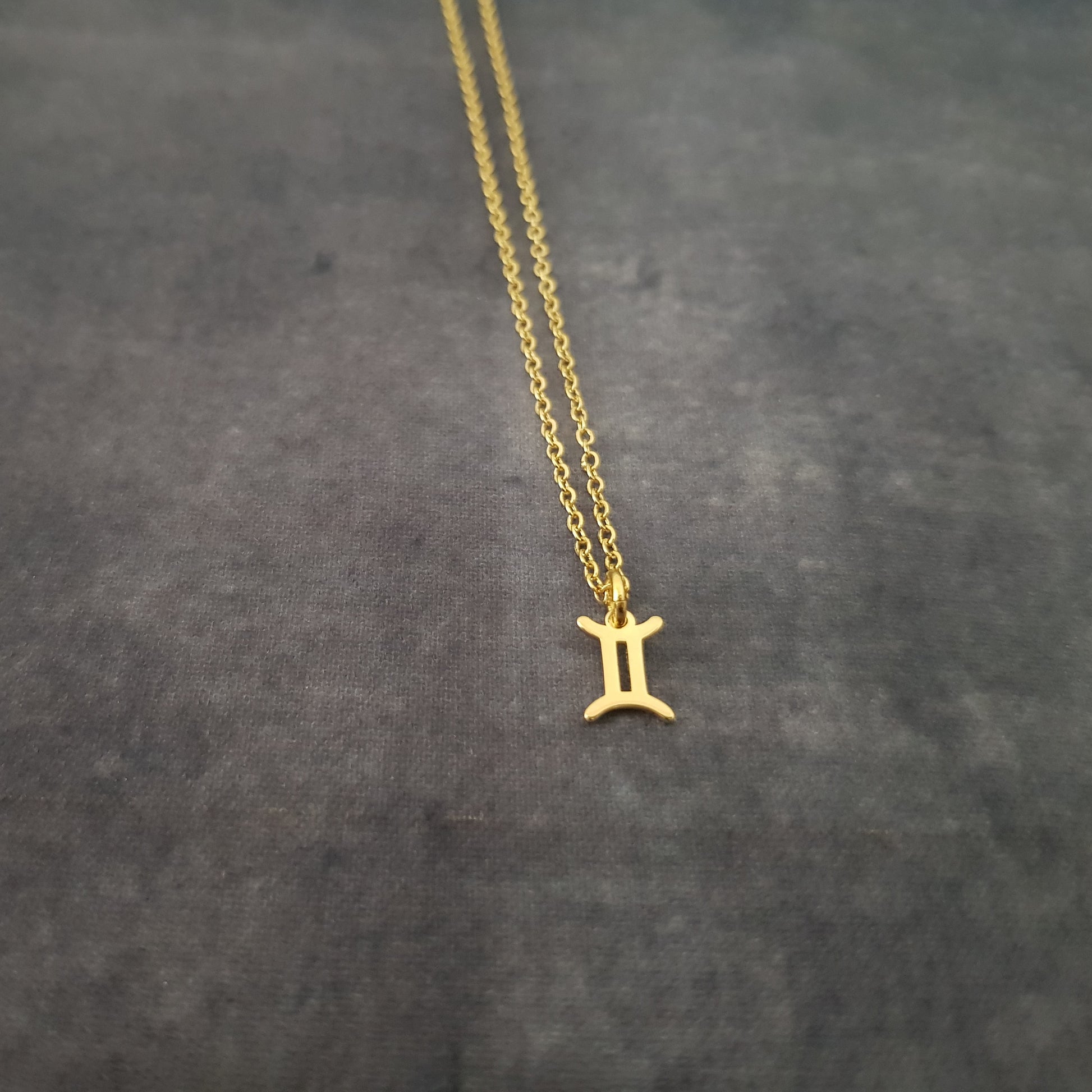 a gold necklace with the letter i on it