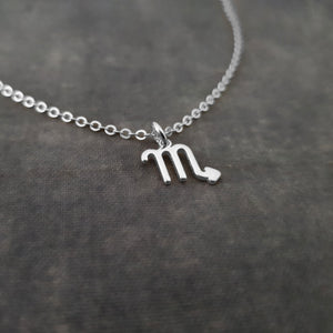 a silver necklace with the letter m on it