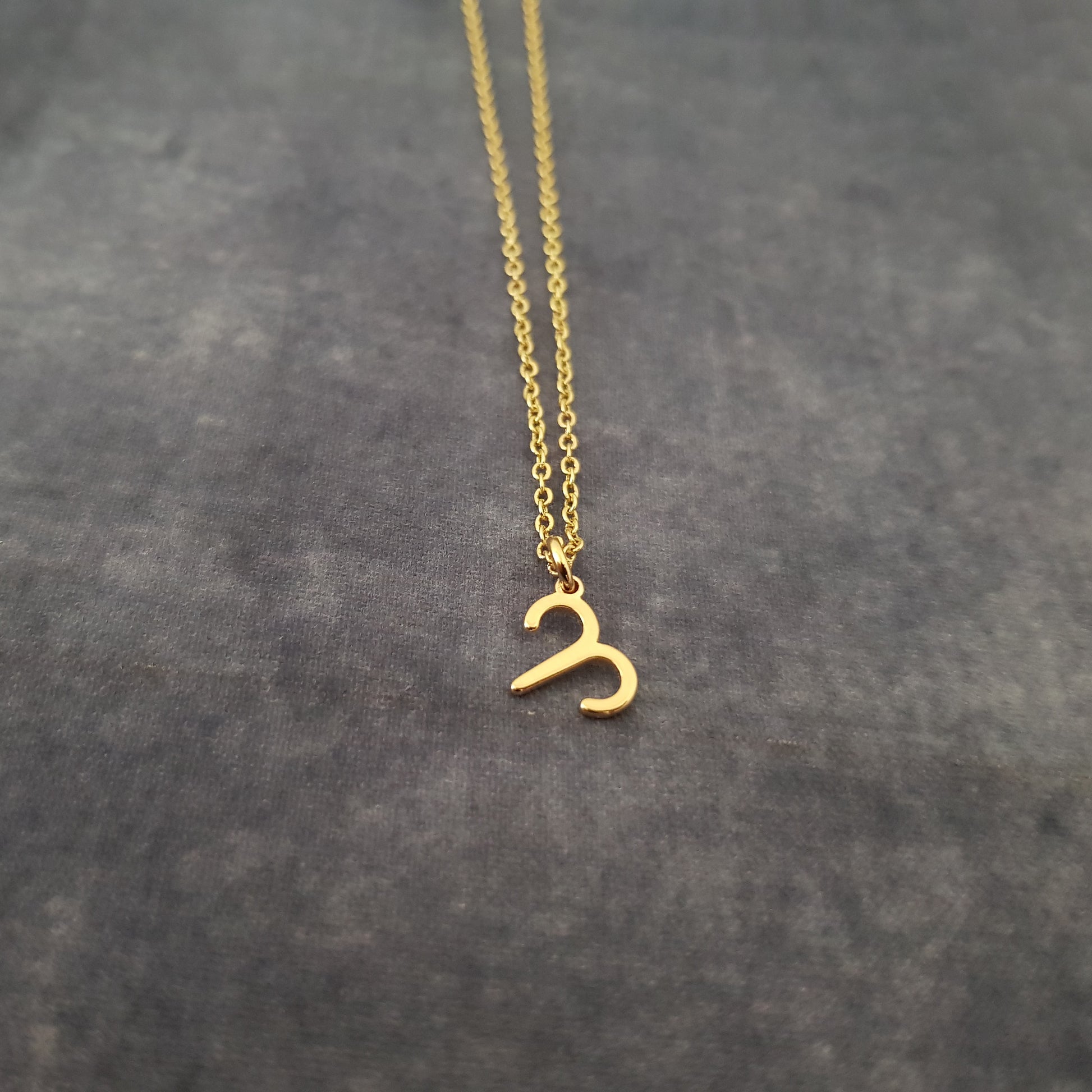 a gold necklace with the letter c on it